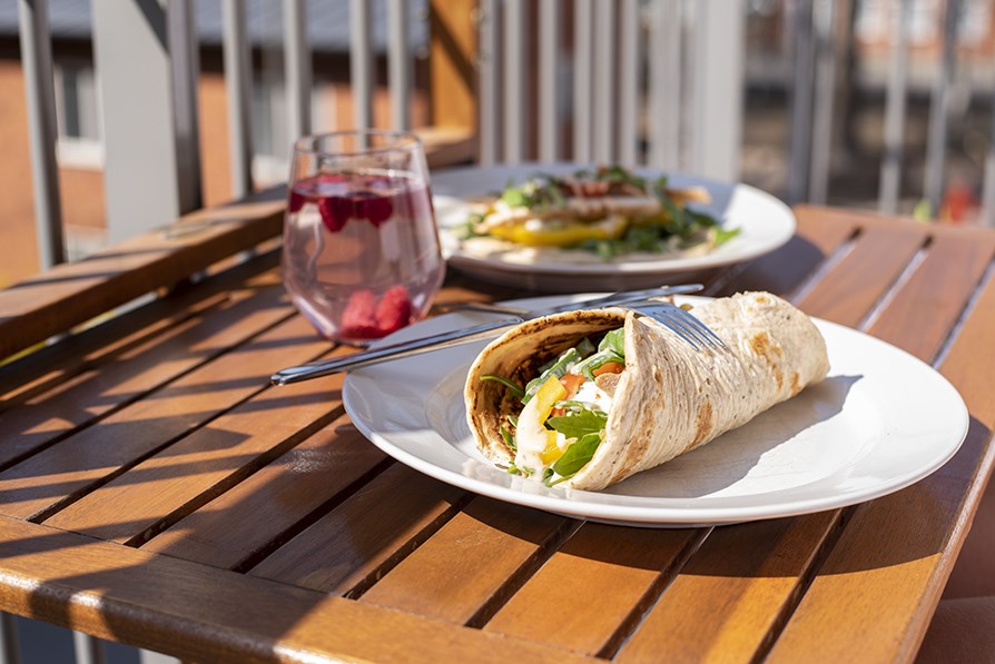 Valmis tytetty wrap ja lasillinen mehua auringossa parvekepydll.