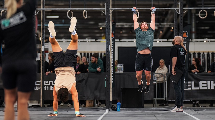 Kuva kahdesta miehest treenaamassa CrossFiti, toinen ksilln seisten ja toinen roikkuen renkaissa.